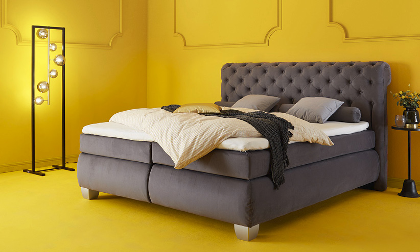 graues Bett in gelbem Schlafzimmer