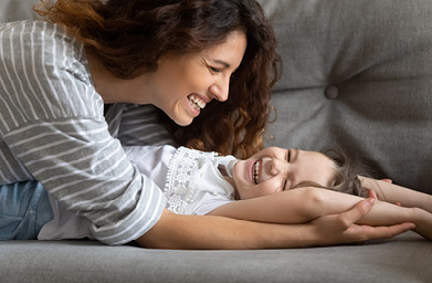 Frau und Kind lachend auf SOfa